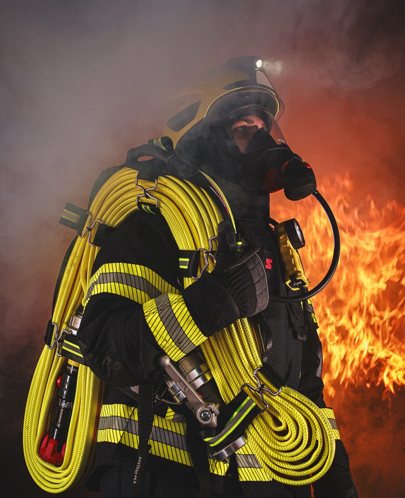 Feuerwehrmann in S-Gard Bekleidung mit Atwmschutz, Helm und dem neuen G&H Schlauchpaket über die Schultern geworfen